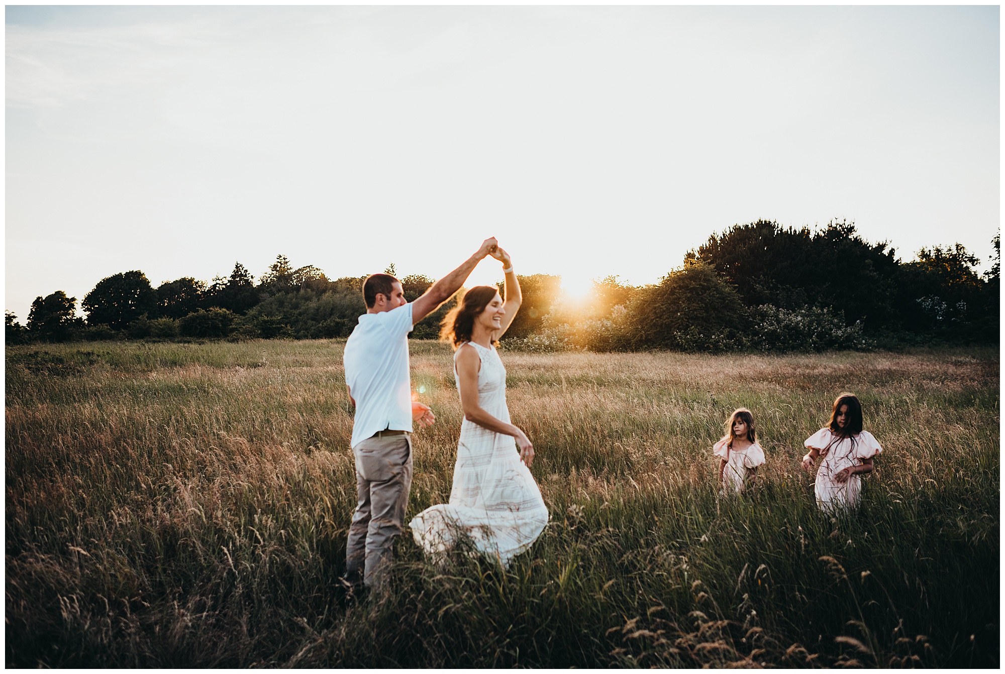 mom and dad dance while little girls watch in field at sunset Emily Ann Photography Seattle Family Photographer